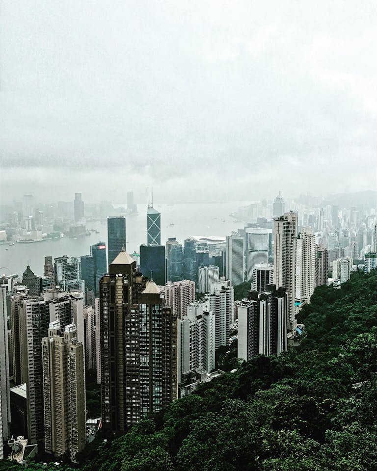 Aerial view of Hong Kong skyscrapers and Victoria Harbour from Victoria Peak on a foggy day.