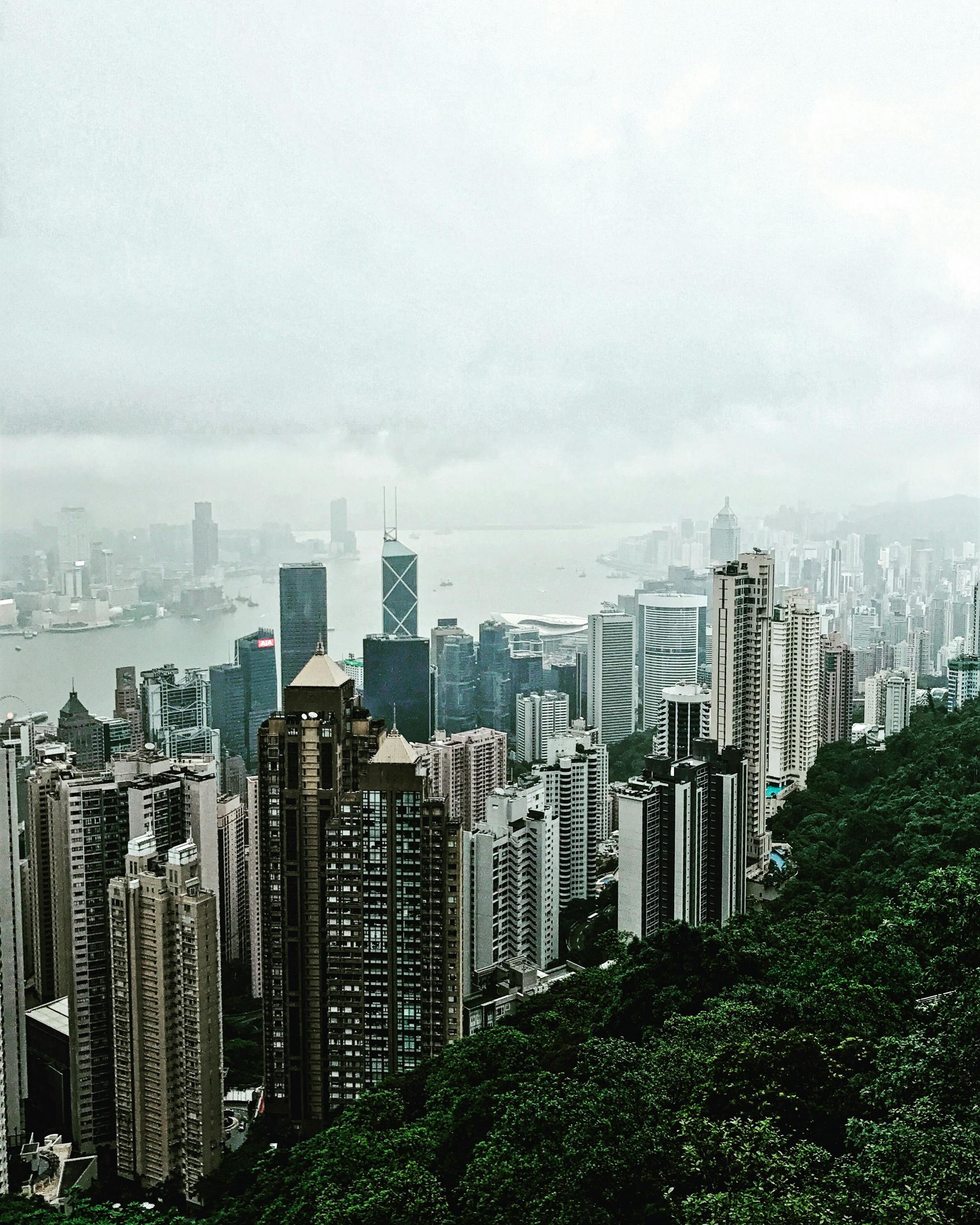 Aerial view of Hong Kong skyscrapers and Victoria Harbour from Victoria Peak on a foggy day.